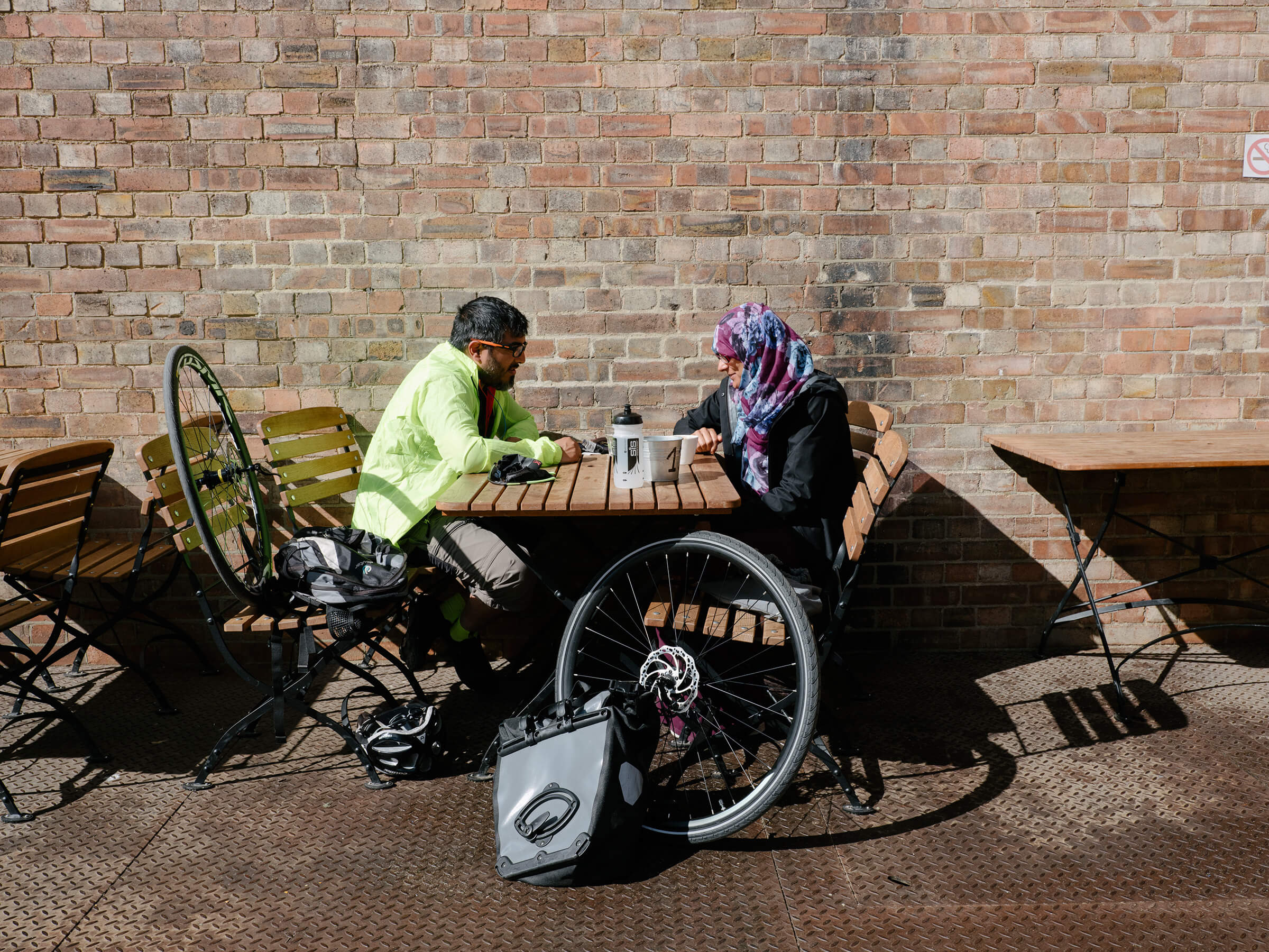 Two cyclists sat in outdoor cafe